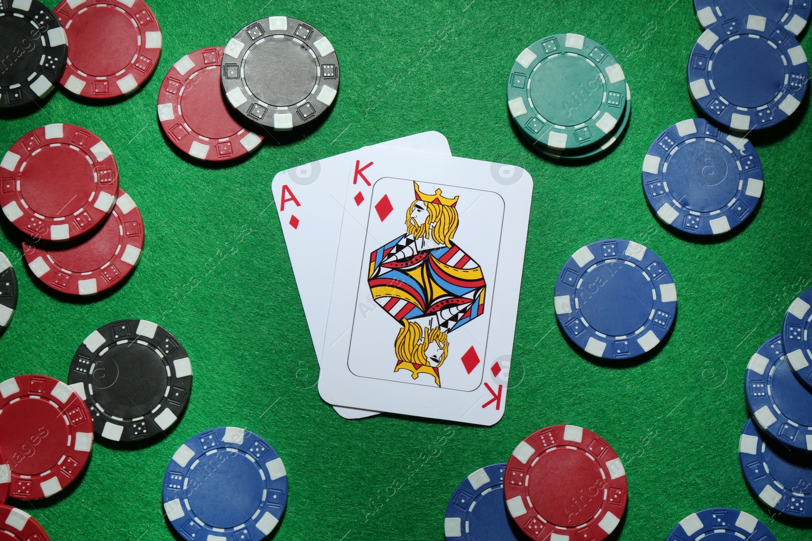 Photo of Poker chips and playing cards on green table, flat lay