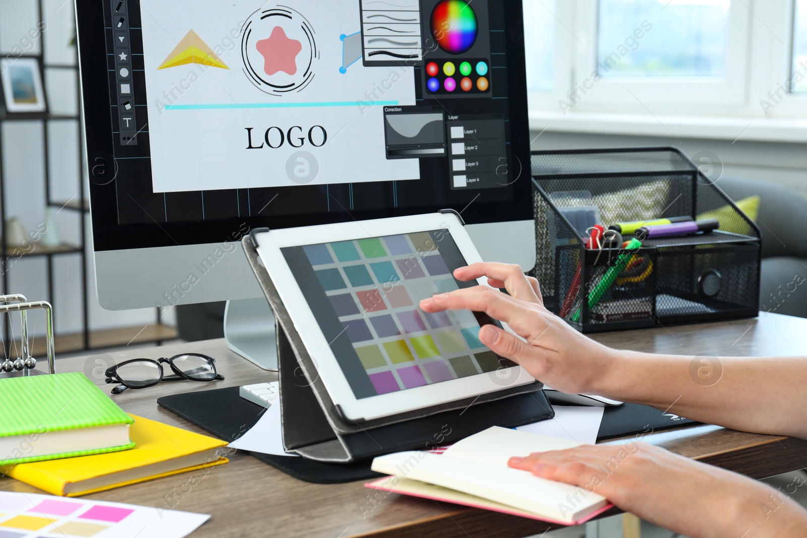 Photo of Designer working on tablet at wooden table indoors, closeup