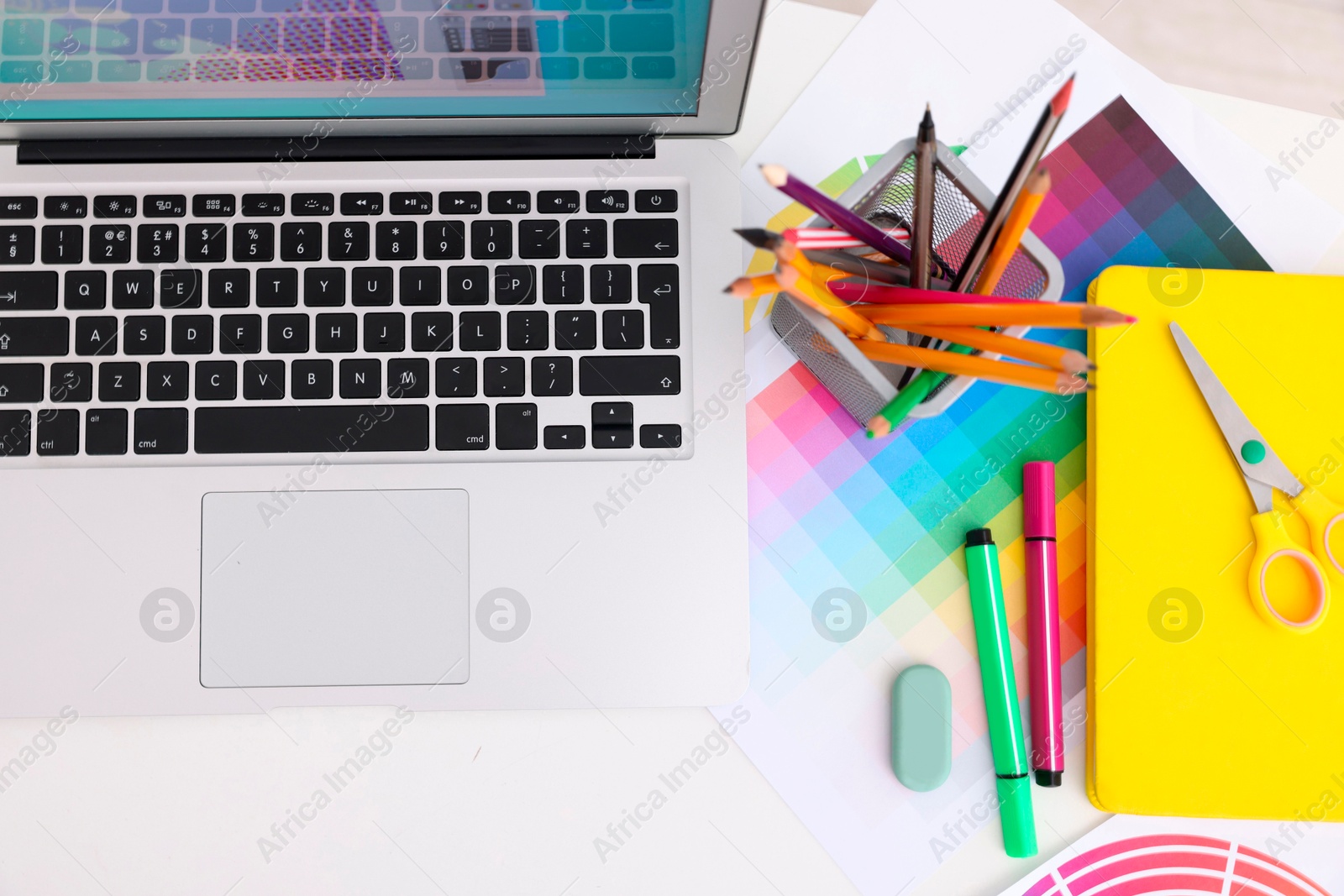 Photo of Designer's workplace with laptop, color palette and stationery on white table, flat lay