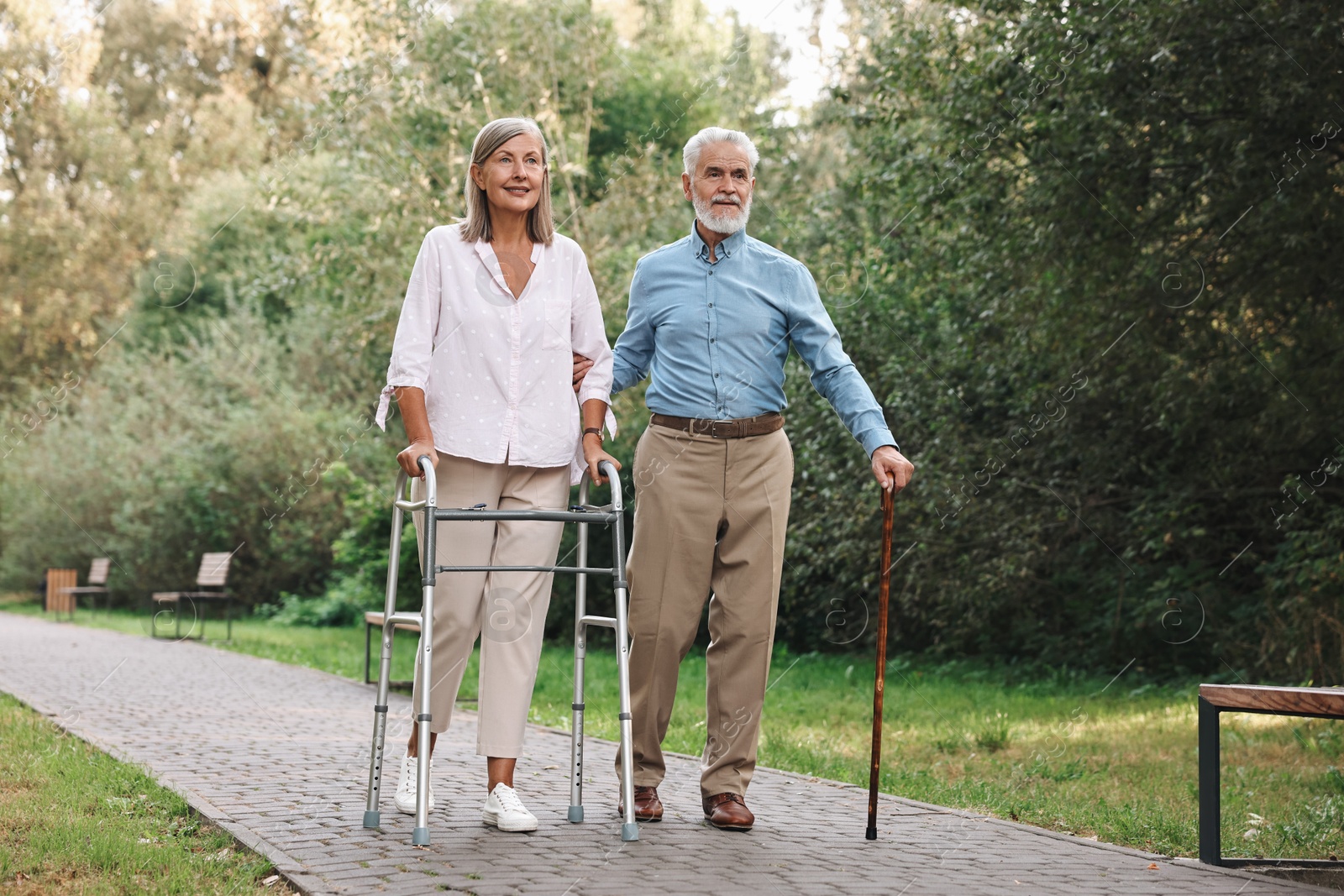 Photo of Senior couple with walking frame and cane in park