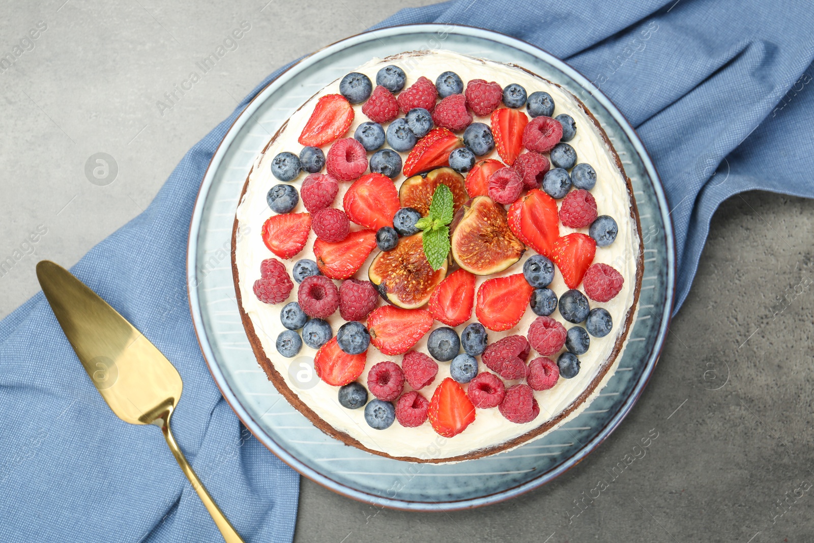 Photo of Delicious chocolate sponge cake with berries and server on grey table, top view