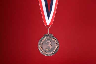 Photo of Bronze medal with striped ribbon on red background