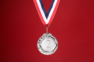 Photo of Silver medal with striped ribbon on red background