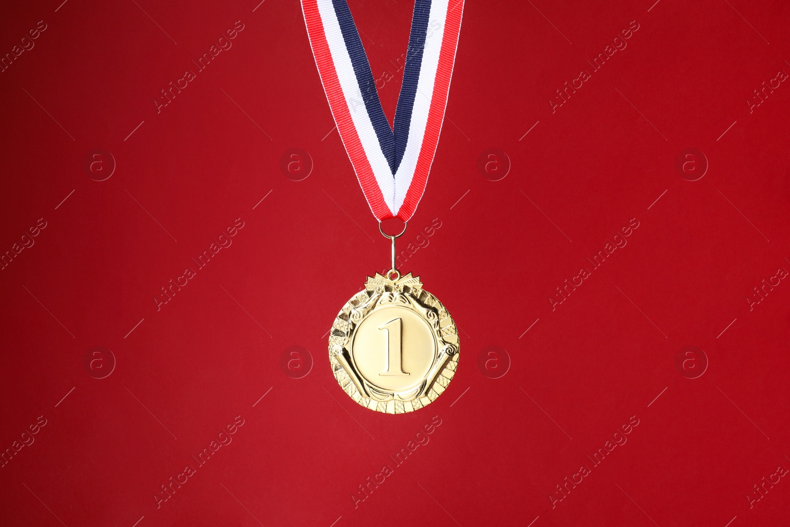 Photo of Golden medal with striped ribbon on red background