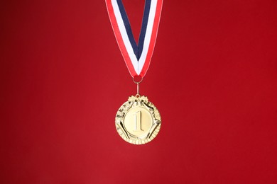 Photo of Golden medal with striped ribbon on red background