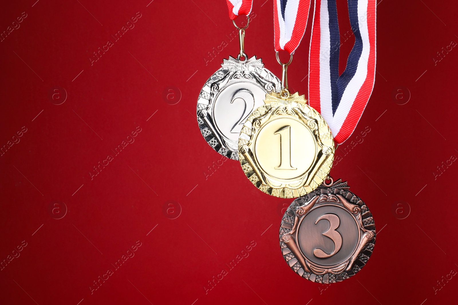 Photo of Golden, silver and bronze medals on red background, space for text