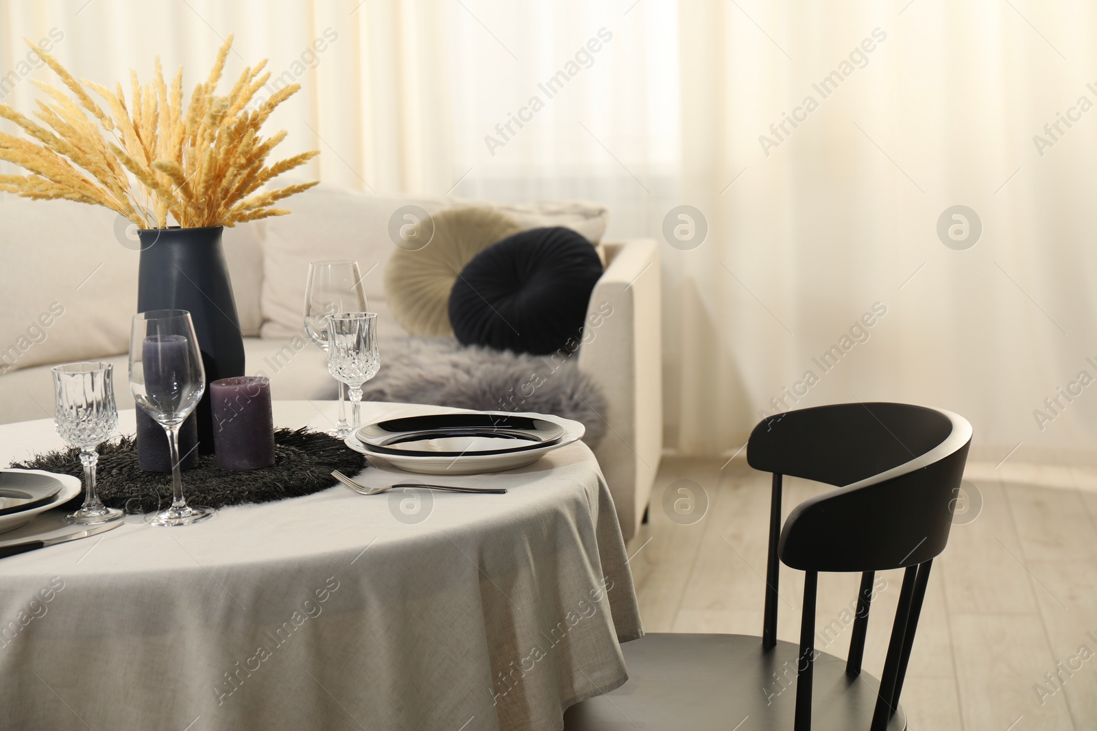 Photo of Stylish table setting with beautiful dishware and black chair in dining room