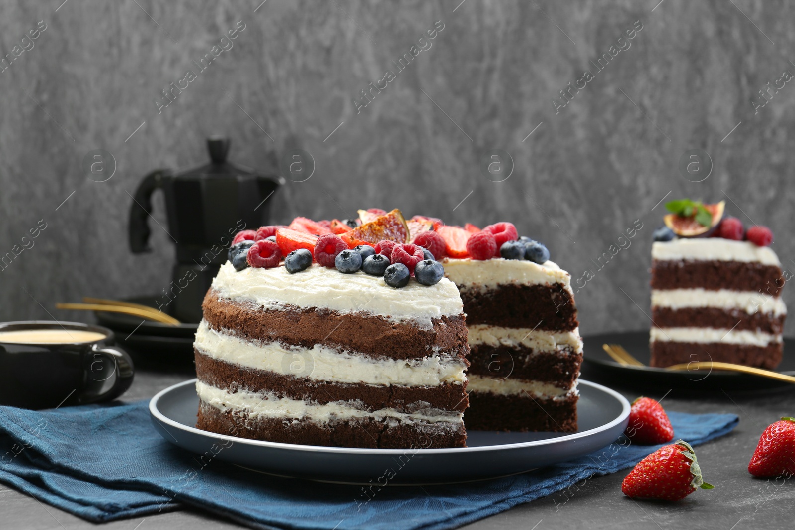 Photo of Delicious chocolate sponge cake with berries served on black table