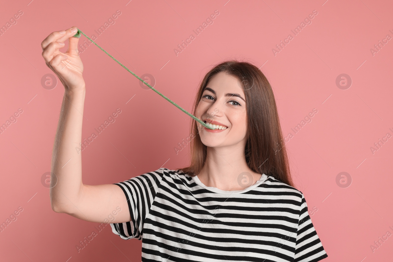 Photo of Young woman eating tasty gummy candy on pink background