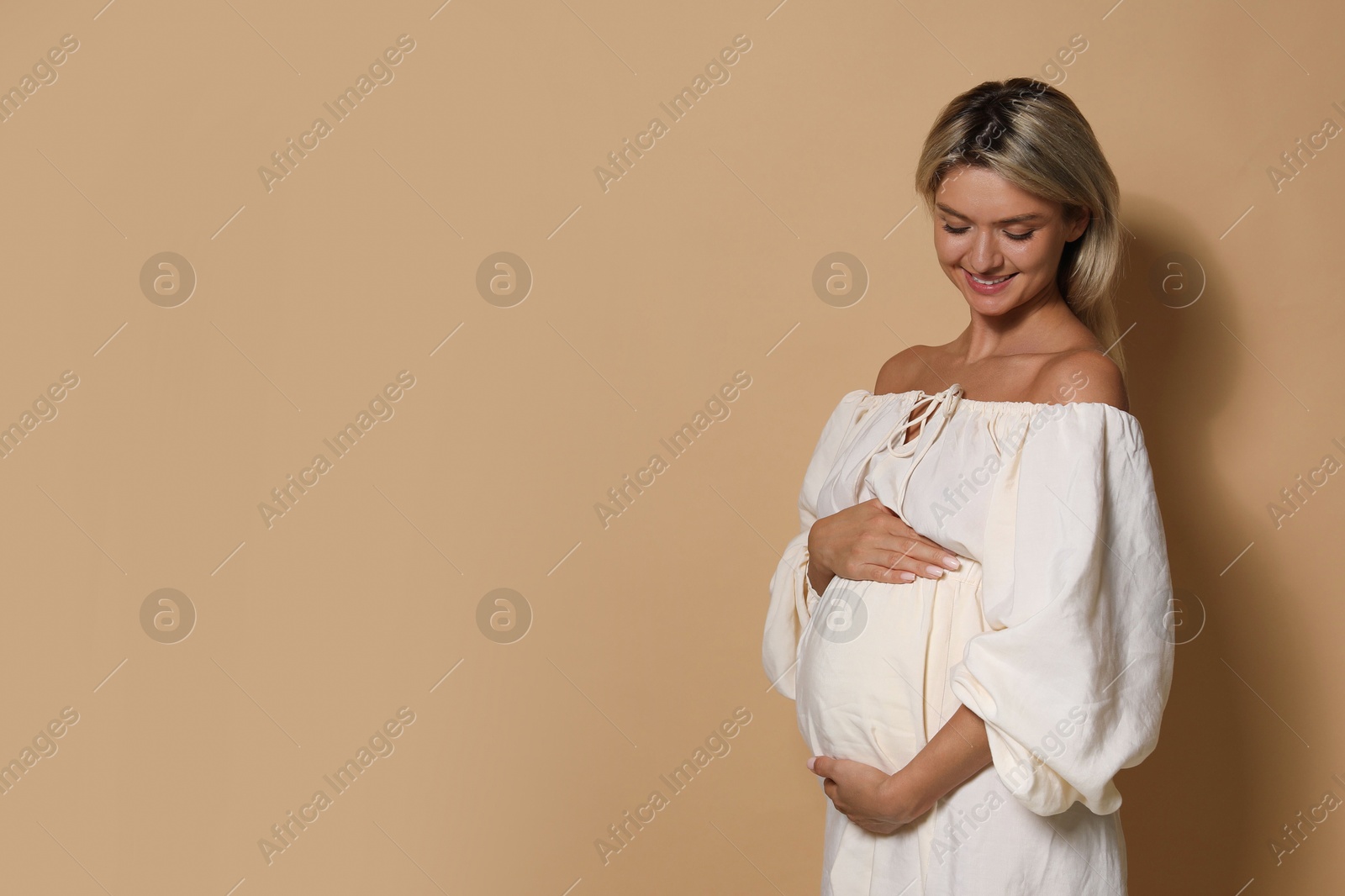 Photo of Portrait of beautiful pregnant woman on beige background, space for text