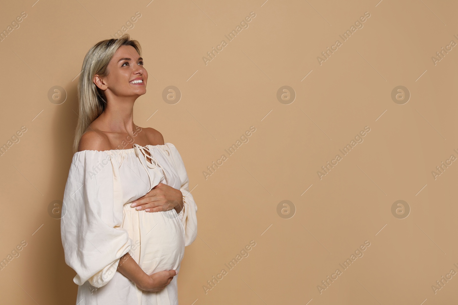 Photo of Portrait of beautiful pregnant woman on beige background, space for text