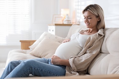 Portrait of beautiful pregnant woman on sofa at home