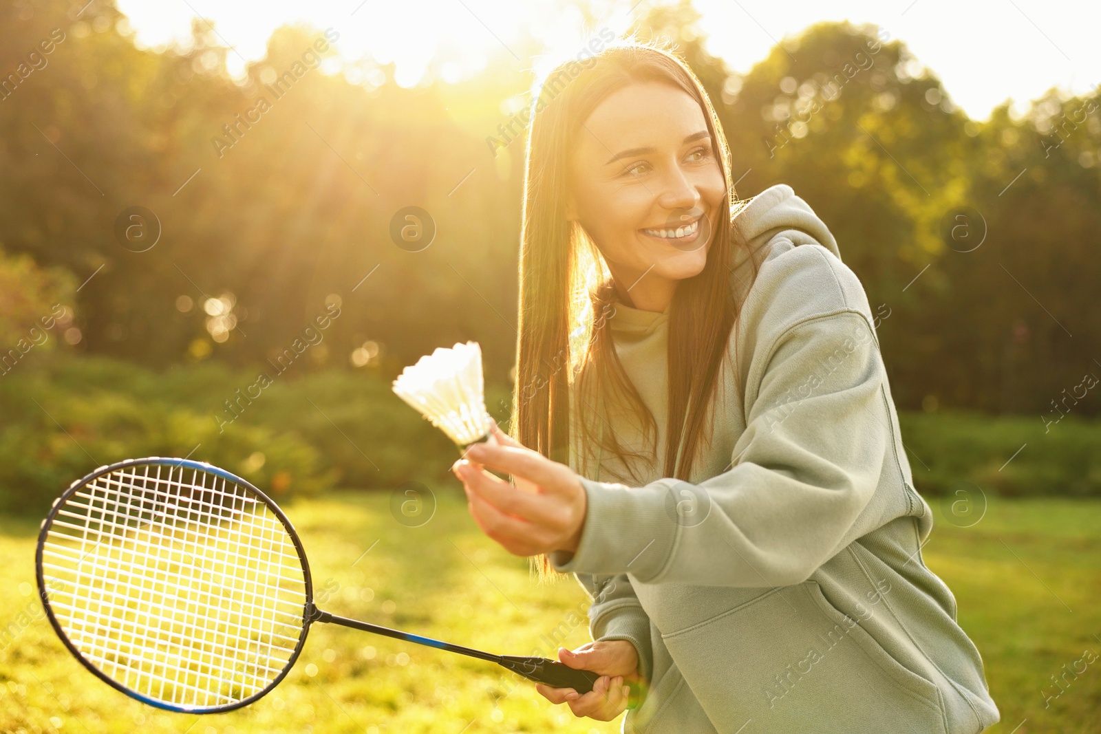 Photo of Happy young woman playing badminton racket in park on sunny day