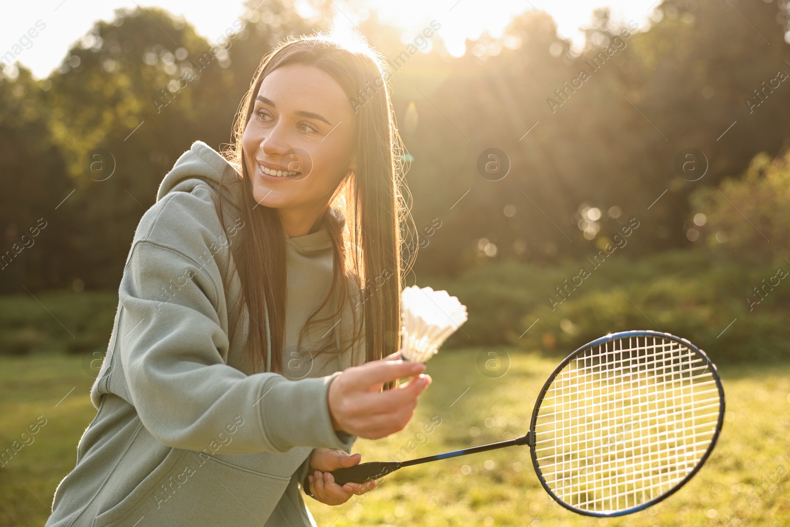 Photo of Happy young woman playing badminton racket in park on sunny day