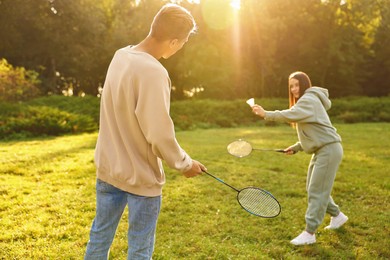 Young woman and man playing badminton in park on sunny day, selective focus