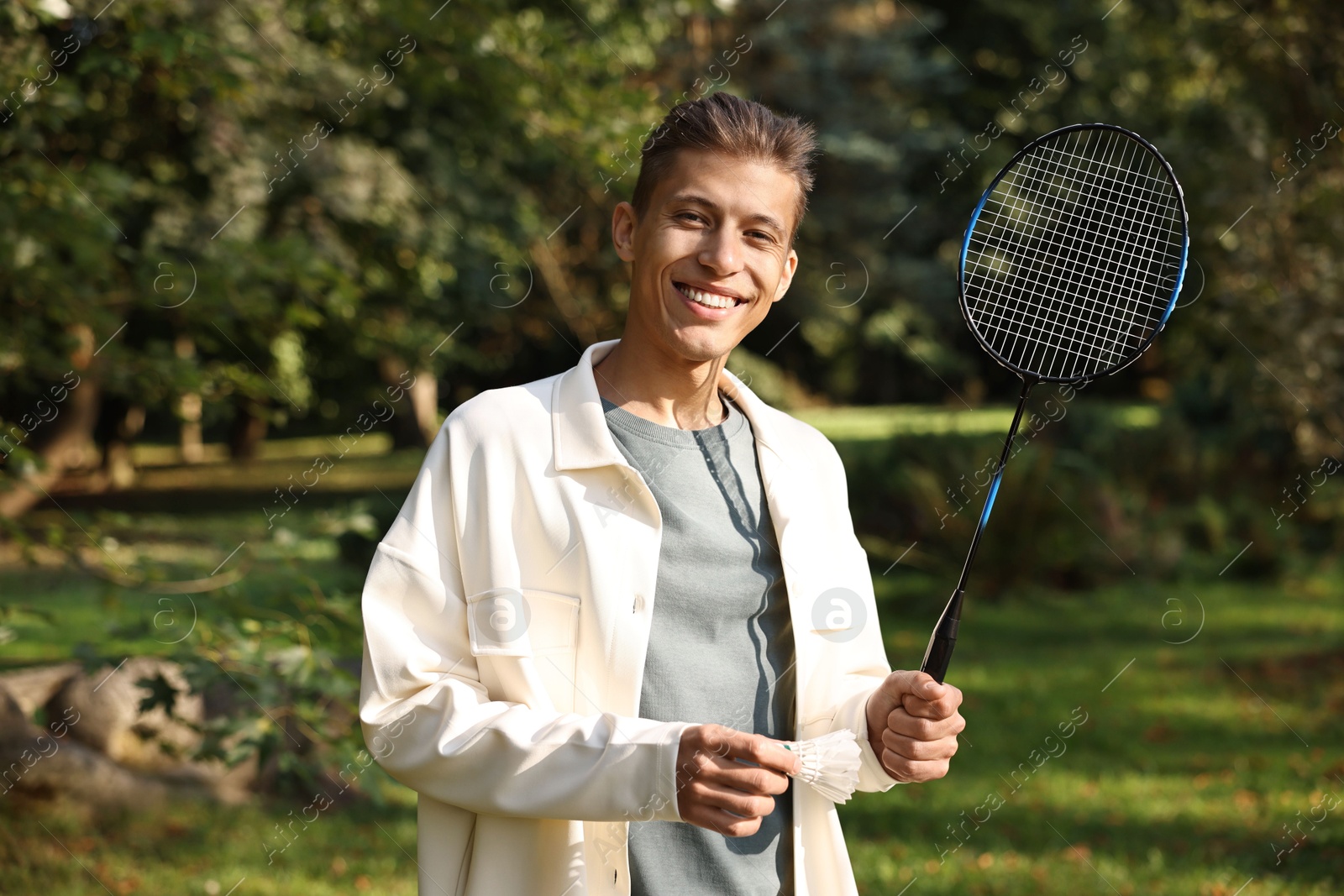 Photo of Happy young man with badminton racket in park