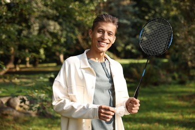 Photo of Happy young man with badminton racket in park