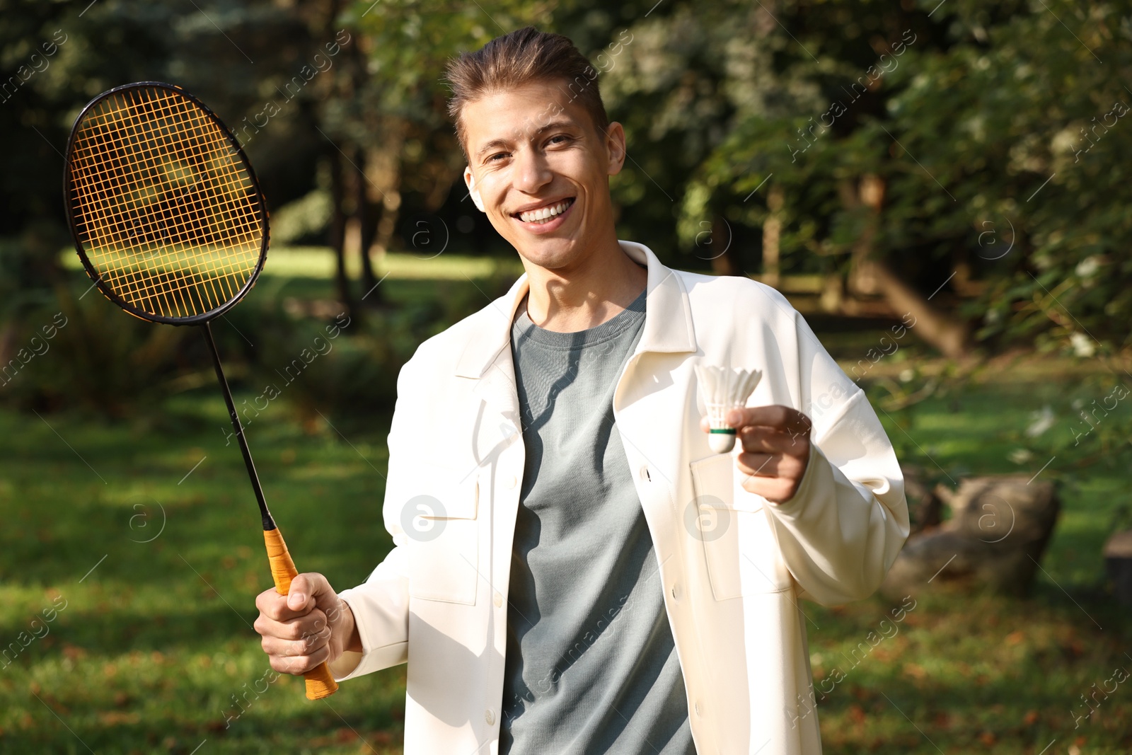 Photo of Happy young man with badminton racket and shuttlecock in park