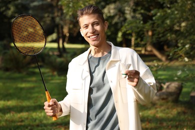 Photo of Happy young man with badminton racket and shuttlecock in park