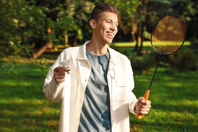 Photo of Happy young man with badminton racket and shuttlecock in park