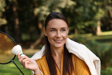 Photo of Happy young woman with badminton racket and shuttlecock in park