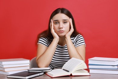 Photo of Young student having stress before exam at desk against red background