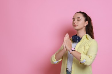 Photo of Young student praying for good exam result on pink background, space for text