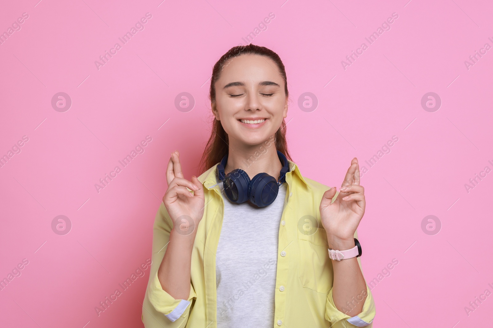 Photo of Excited young student crossing fingers on pink background. Hope for good exam result