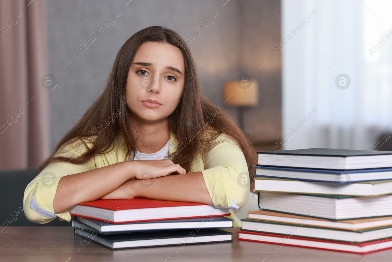 Photo of Young student with books having stress before exam at wooden table