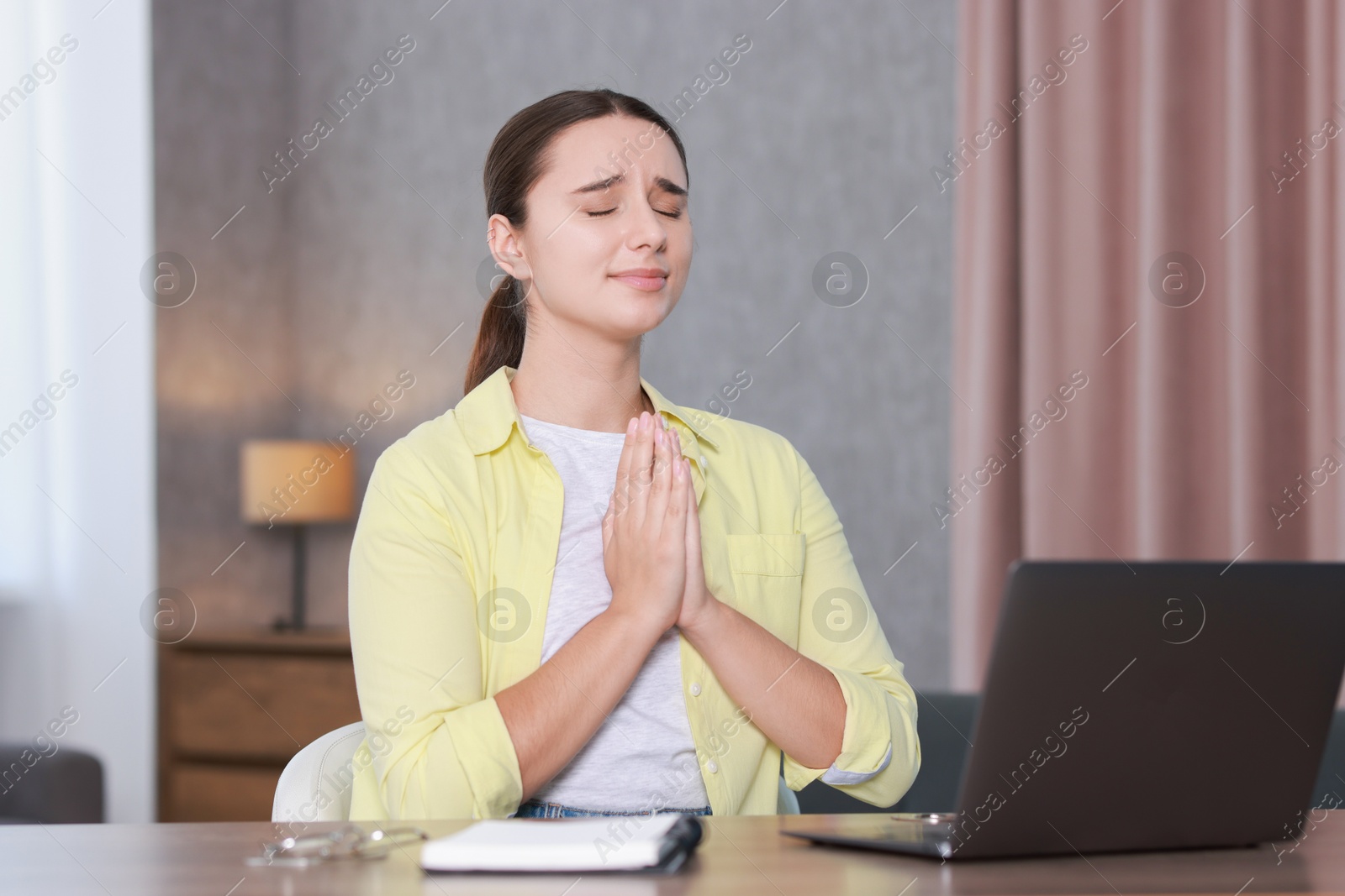 Photo of Young student praying for good exam result at workplace