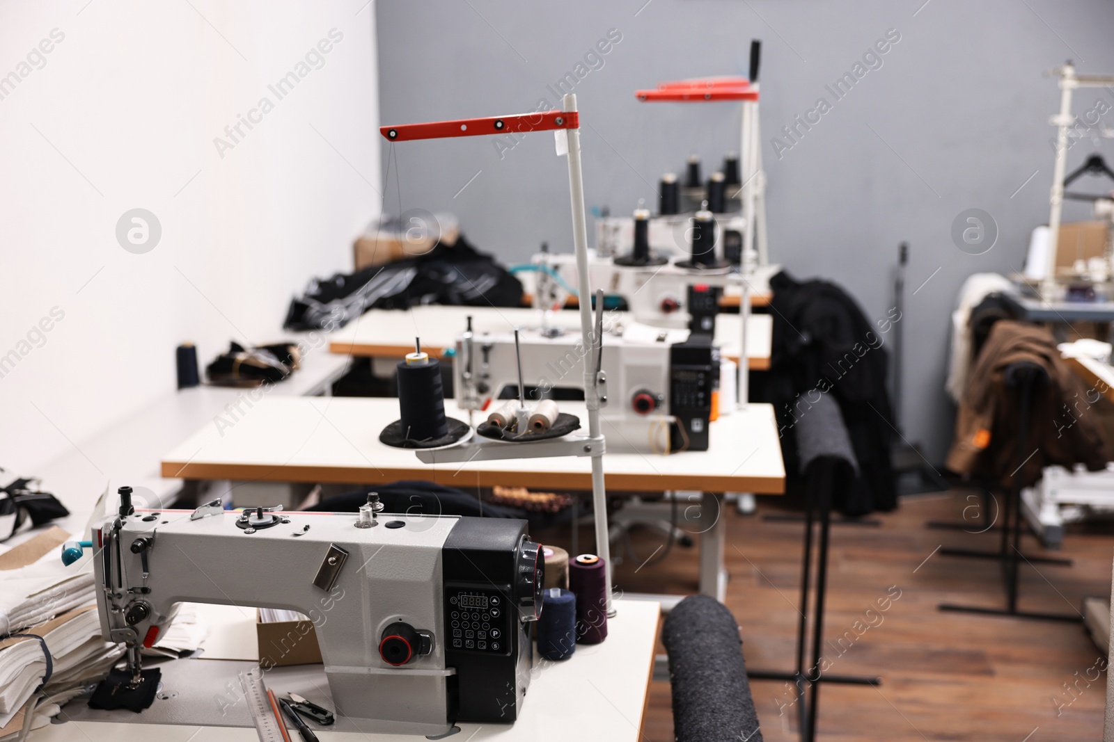 Photo of Sewing machines with spools of thread in professional workshop