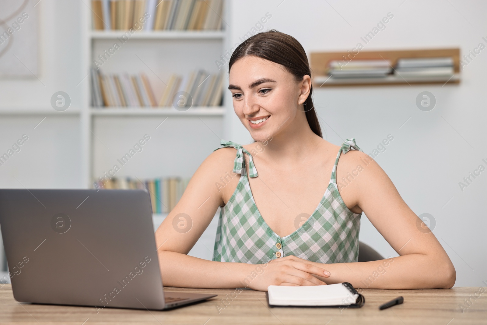 Photo of Student feeling happy about her good exam result at table with laptop indoors