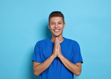 Photo of Happy student praying for good exam result on light blue background