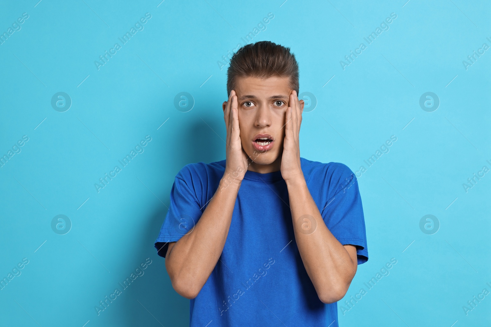 Photo of Emotional student having stress before exam on light blue background