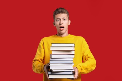 Photo of Emotional student with stack of books having stress before exam on red background