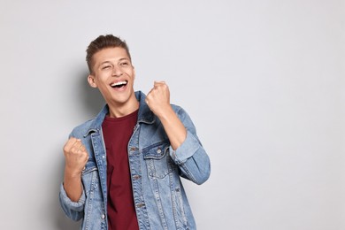 Photo of Student feeling happy about his good exam result on grey background. Space for text