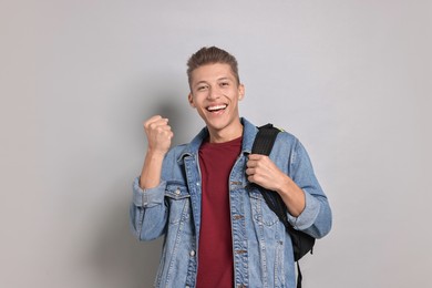 Photo of Student with backpack feeling happy about his good exam result on grey background