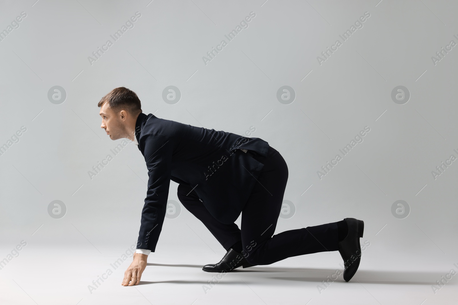 Photo of Businessman in starting position for run on light grey background