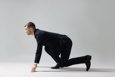 Photo of Businessman in starting position for run on light grey background