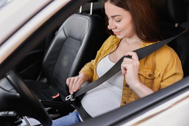 Photo of Pregnant woman fastening safety belt in car, view from outside