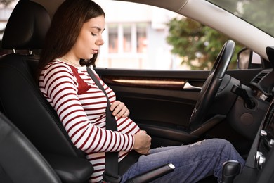 Pregnant woman with safety belt driving car