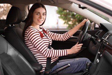 Photo of Smiling pregnant woman with safety belt driving car