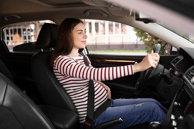 Photo of Pregnant woman with safety belt driving car