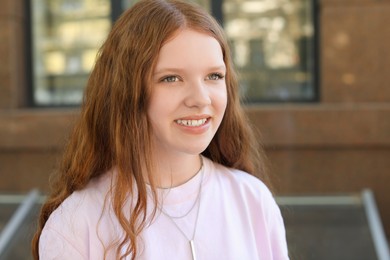 Photo of Portrait of happy teenage girl with long hair outdoors