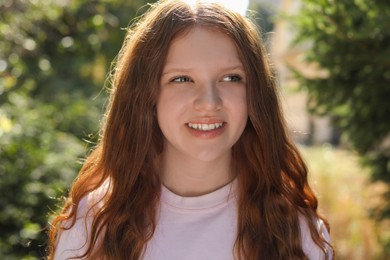 Portrait of happy teenage girl with long hair outdoors