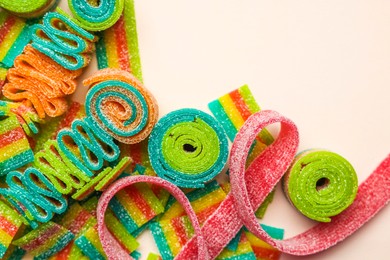 Different tasty sour belts on beige background, top view