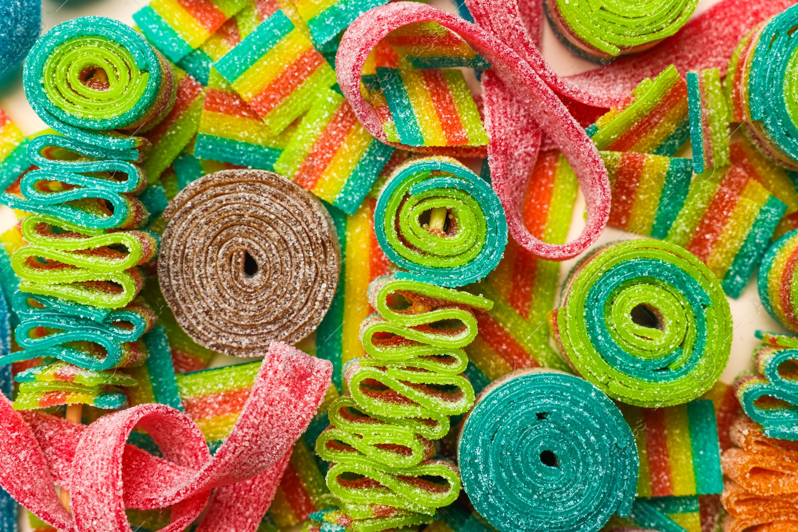 Photo of Different tasty sour belts as background, top view