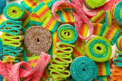 Photo of Different tasty sour belts as background, top view