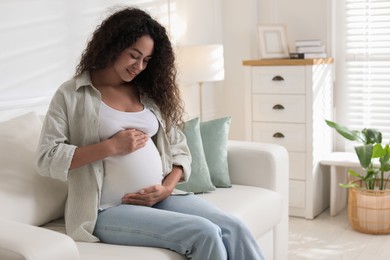 Portrait of beautiful pregnant woman on sofa at home