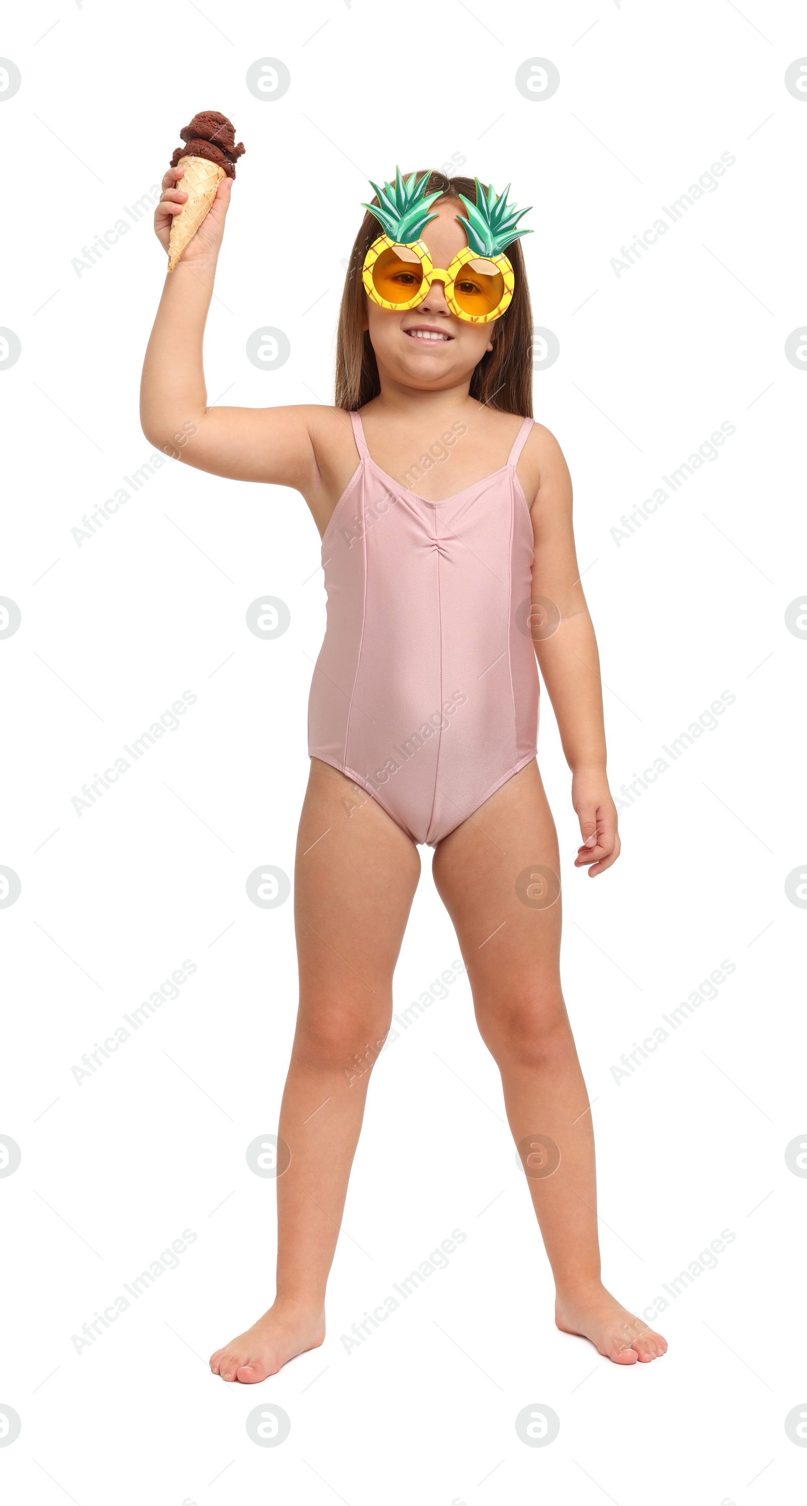 Photo of Cute little girl in swimsuit with funny sunglasses eating ice cream on white background